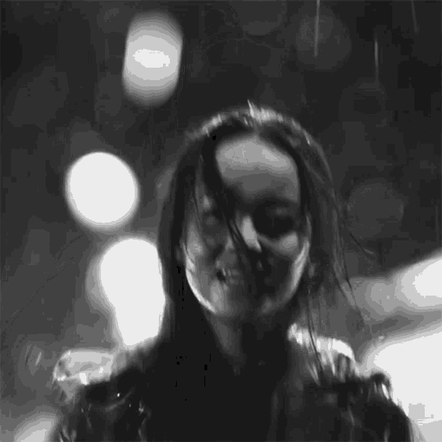 a black and white photo of a woman in the rain with her hair blowing in the wind .