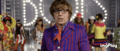 Austin Powers stands before dancing performers beneath “OOPS! I DID IT AGAIN.”