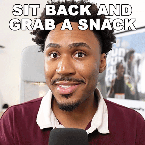 a man in a maroon shirt with the words sit back and grab a snack above him