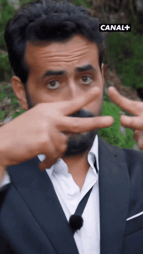a man in a suit and tie is making a peace sign with his hands