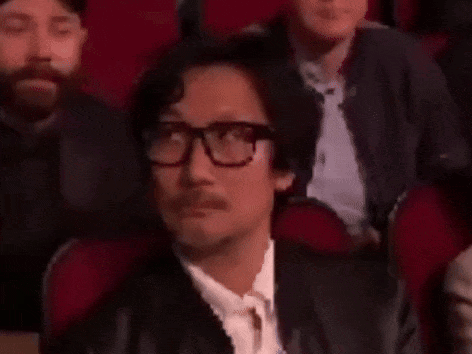 a man wearing glasses and a mustache is sitting in a theatre .