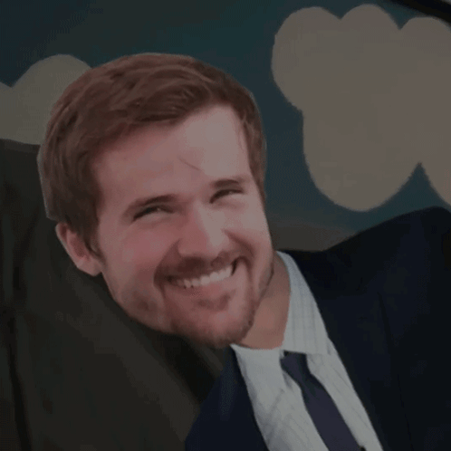 a man with a beard wearing a suit and tie is smiling