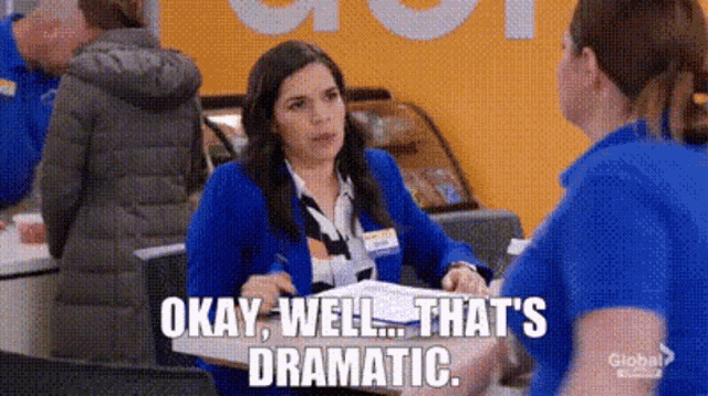 a woman in a blue jacket is sitting at a counter in a store and talking to another woman .