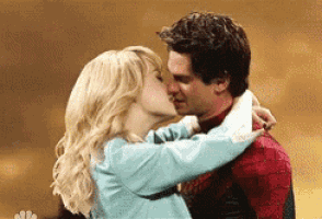 a man and a woman are kissing in front of a brown background .