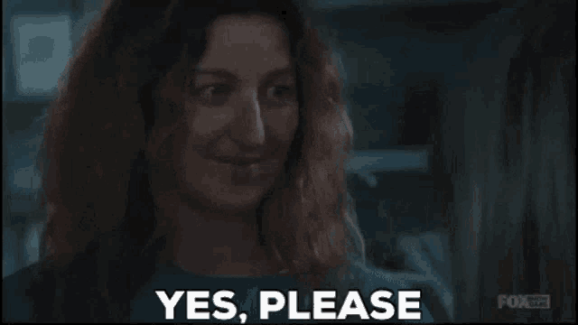 a woman is smiling and saying yes please in a dark room