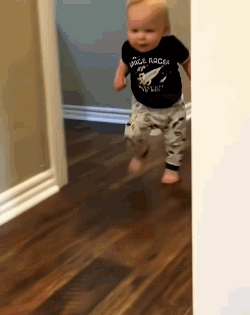 A toddler in a hallway turns and runs away.