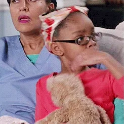 An elderly woman clutches her chest in offended surprise.