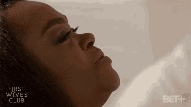 a woman laying on a bed with the words first wives club behind her