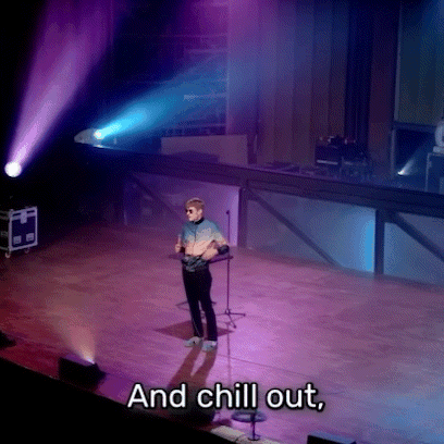 A person stands alone under purple and blue stage lights with the subtitle “And chill out.”