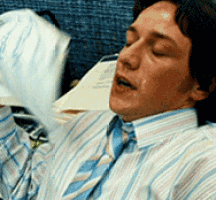 A man lies in bed, sweating and looking anxious.
