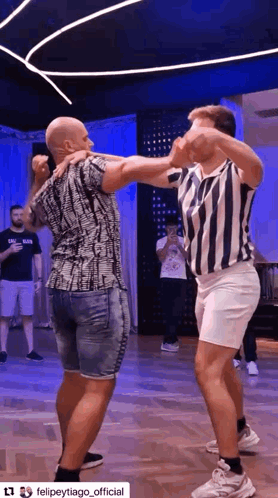 two men are dancing together on a dance floor in a room .