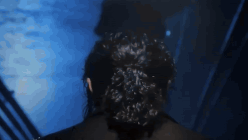 a woman with a bun in her hair is standing in a dark room