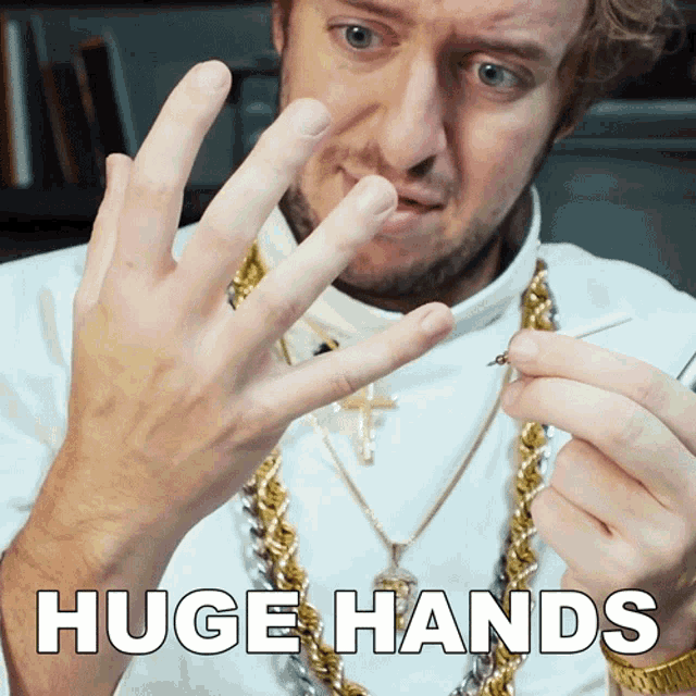 a man wearing gold chains and a cross necklace has huge hands