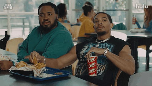 two men sitting at a table with a hulu logo in the corner