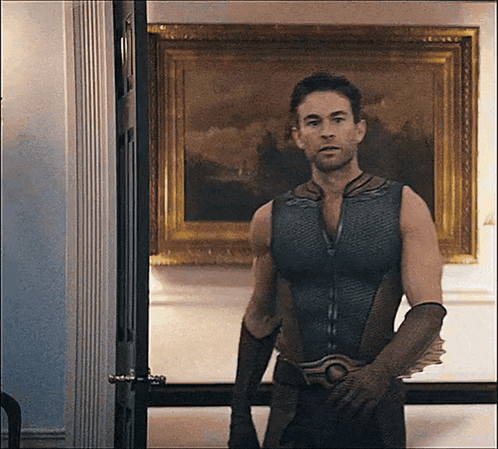 a man in a superhero costume is standing in front of a painting on the wall .