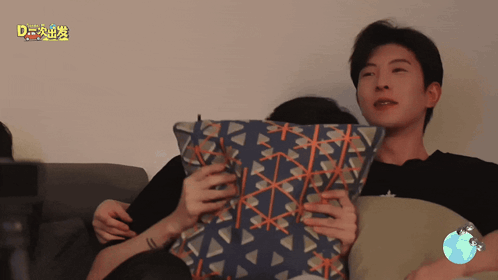 a man is holding a pillow in front of a sign that says " d " on it