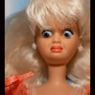 A Barbie doll has bulging eyes and a shocked expression.