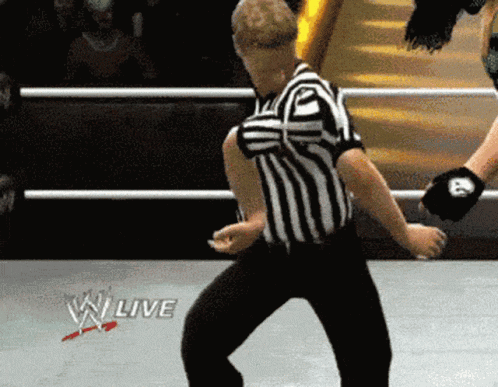 A wrestling referee gives a thumbs-up in a WWE ring.
