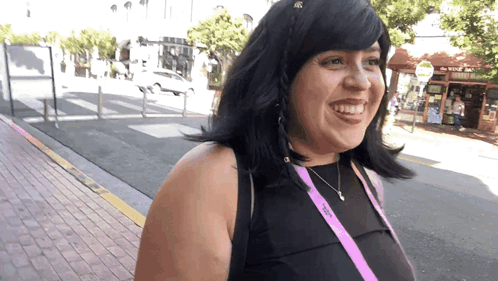 a woman wearing a black top and a purple lanyard that says ' victoria ' on it