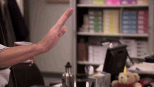 An outstretched hand offers a high five in an office.