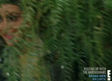 A woman peers through tall grass as if searching for drama.