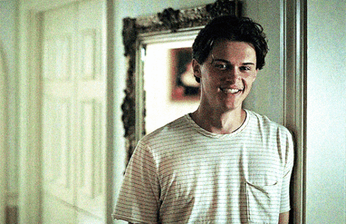 a young man in a striped t-shirt is smiling in a hallway