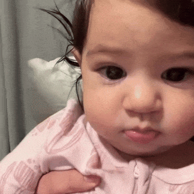 A baby in pink makes a pouty, about-to-cry face.