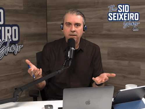 a man is sitting in front of a microphone and a sign that says the sid seixeiro show