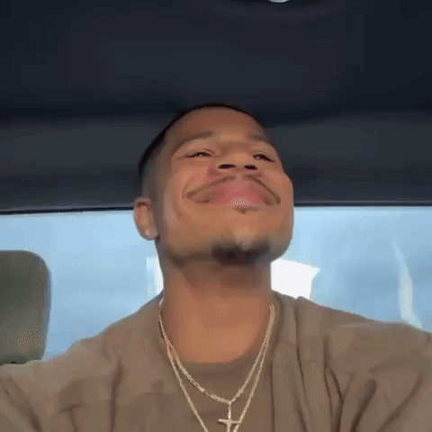 Ace Greene leans back in a car with a satisfied smile.
