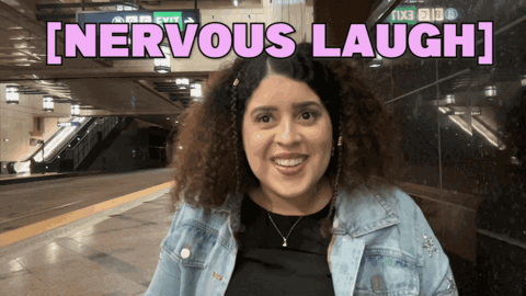 a woman is smiling in front of a sign that says [ nervous laugh ]
