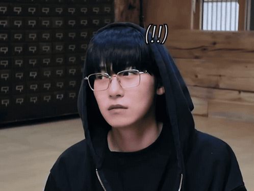 a man wearing glasses and a black hoodie has an exclamation mark on his head