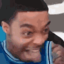a man in a blue jersey is making a funny face while talking on a cell phone .