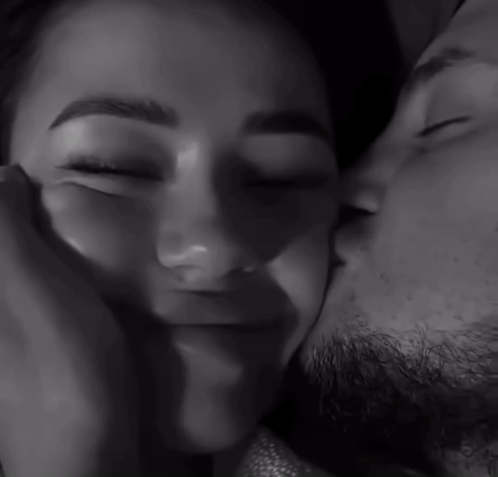 a black and white photo of a man kissing a woman 's forehead