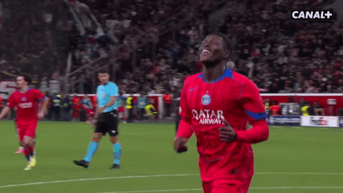 a soccer player wearing a red qatar airlines jersey celebrates