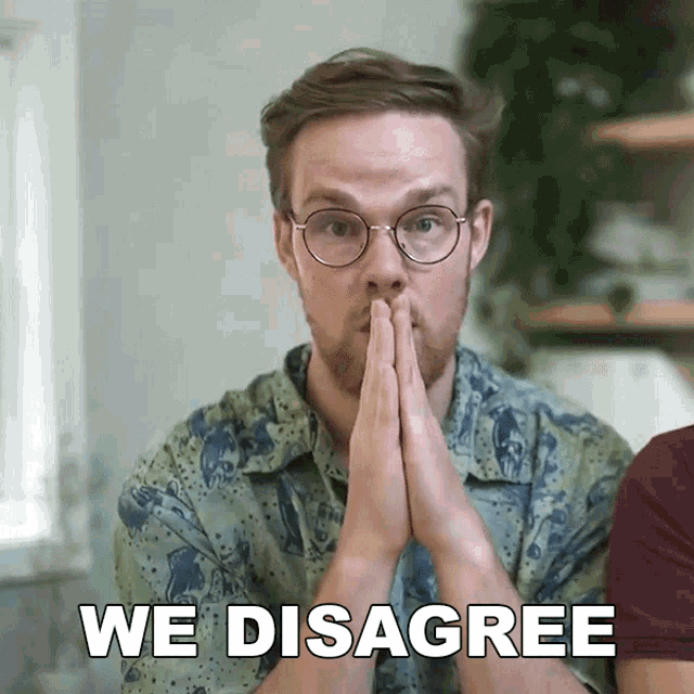 a man wearing glasses says we disagree with his hands folded in front of his face