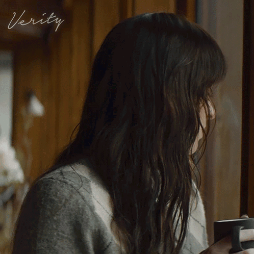 a woman looking out a window with the word verity written on the bottom
