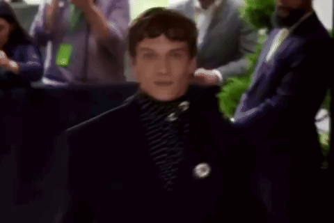 a man in a black suit is standing in front of a crowd .