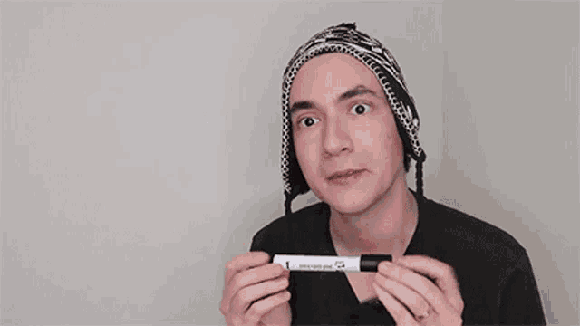 a young man in a hat is holding a marker in his hands .