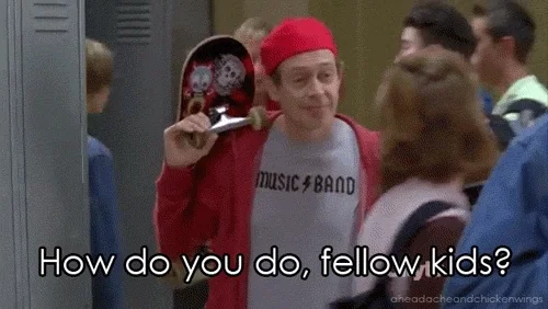 Steve Buscemi wears a red cap and shirt among younger students, captioned “How do you do, fellow kids?”