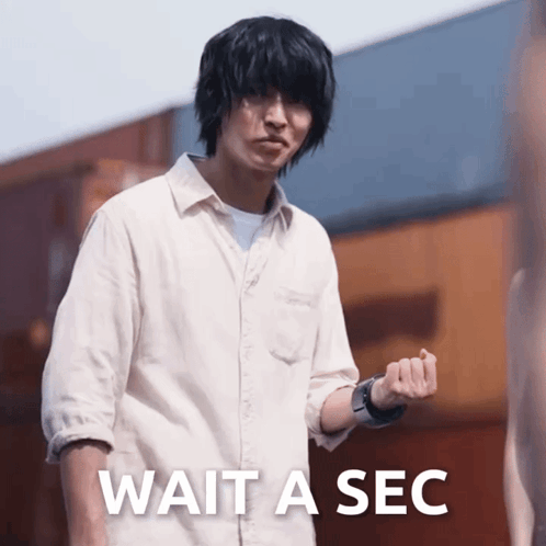 a man in a white shirt stands in front of a sign that says " wait a sec "