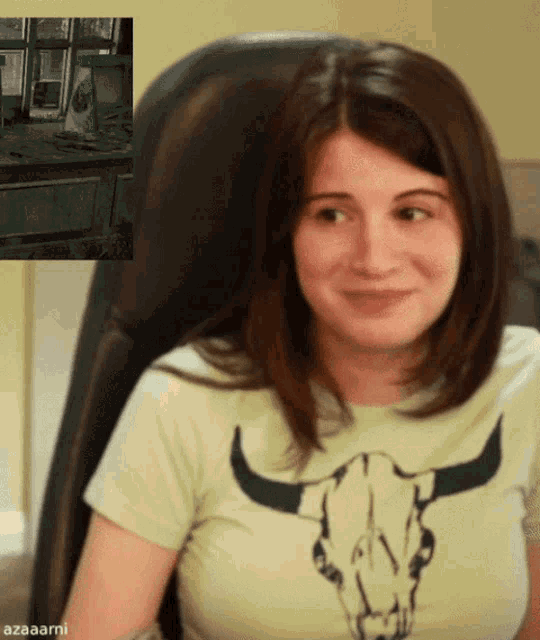 a woman wearing a t-shirt with a bull skull on it sits in a chair