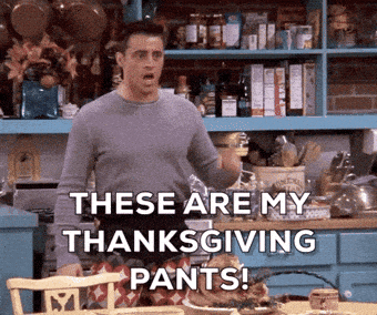 a man is standing in a kitchen with the words these are my thanksgiving pants .