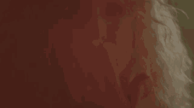 a close up of a person 's face and hair with a red background .