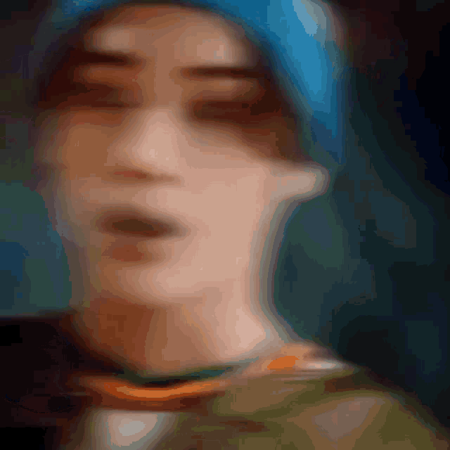 a blurry picture of a person 's face with a blue hat on