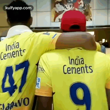 two men are hugging each other and one of them is wearing a yellow india cements jersey .