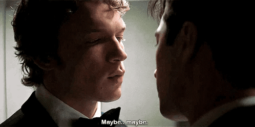 a man in a tuxedo is talking to another man in a suit .