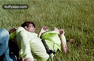 a man and a woman are laying on the grass .