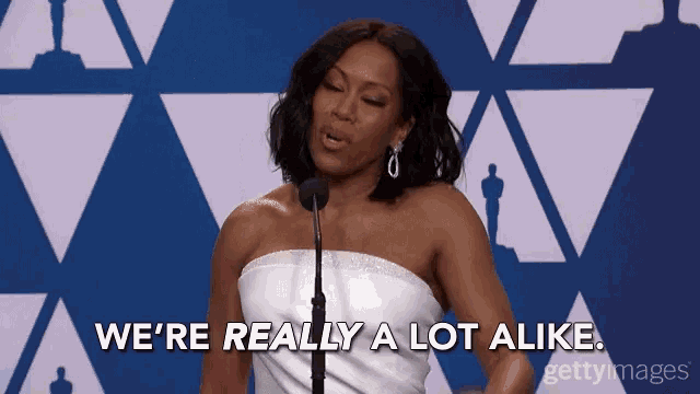 a woman speaking into a microphone with the words we 're really a lot alike behind her