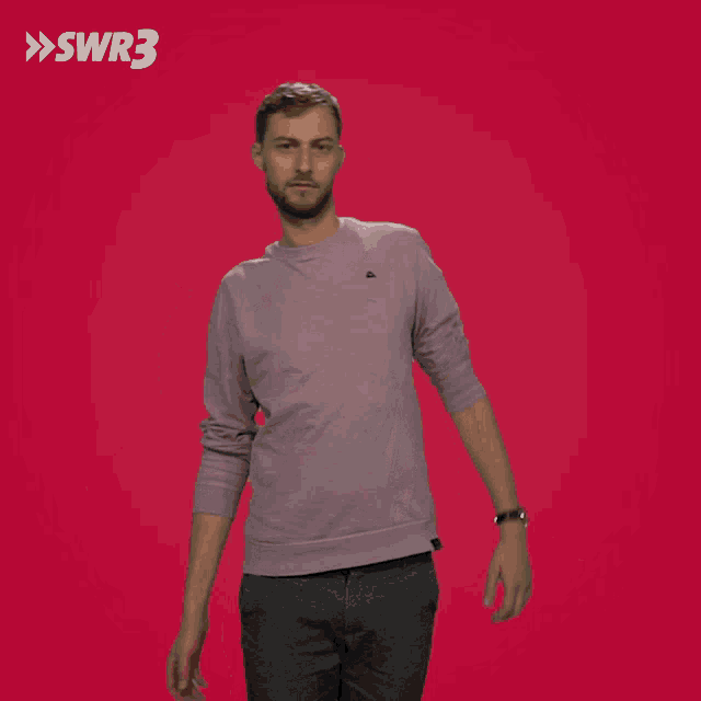 a man in a sweater is standing in front of a red background with swr3 written on it