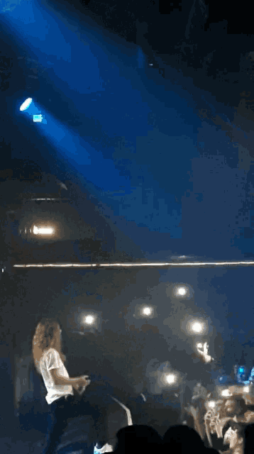 a woman in a white shirt is standing on a stage in front of a crowd